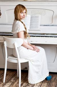 Een vrouw die voor een akoestische piano zit