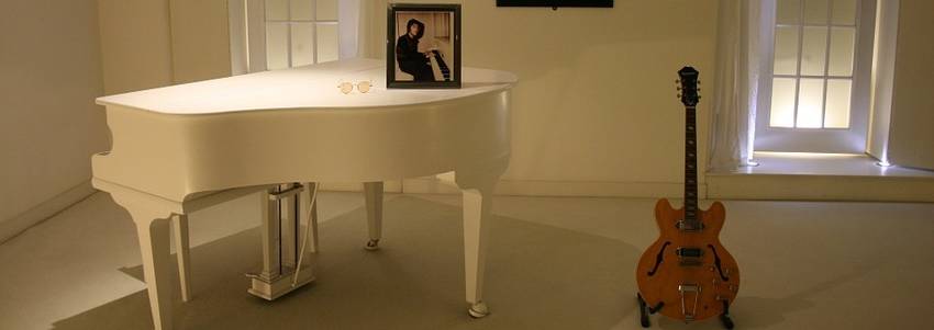 Een witte piano met een gitaar er naast