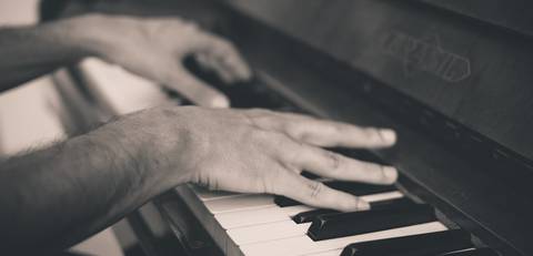 Twee handen die een piano aan het bespelen zijn