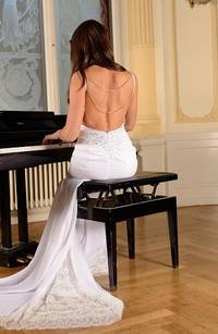 Een vrouw die op een pianostoel zit achter een piano